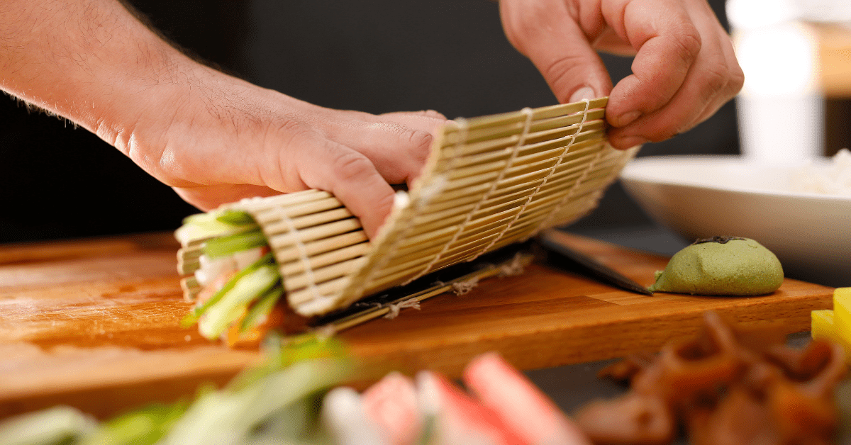 Chef rolling up sushi with a bamboo rolling mat