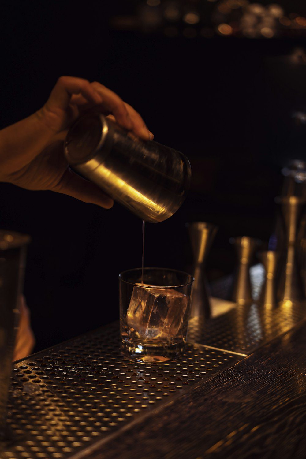 Cocktail shaker pouring into a glass during mixology class